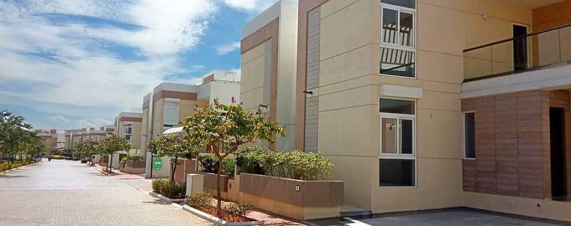 A row of completed villas along a paved internal street – earlier phase, actual photograph